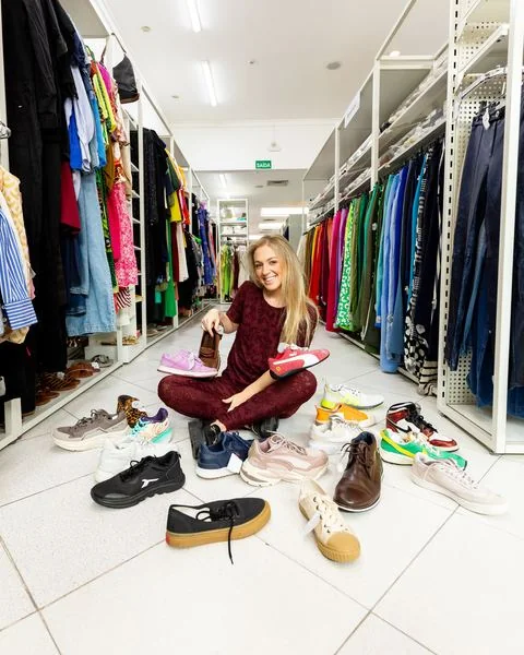 Júlia sentada no chão do brechó entre tênis
