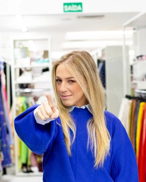 Júlia apontando para a câmera de suéter azul