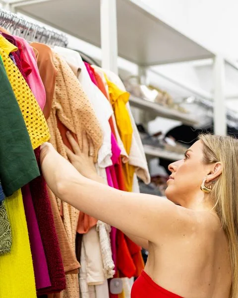 Júlia escolhendo roupas na arara colorida
